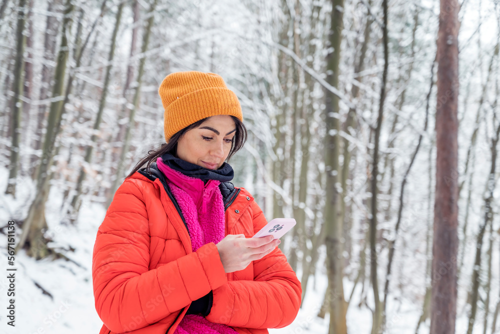 Young Woman using mobile phone in the Snowy Winter Mountain .Woman using trail map in the forest Young Woman using mobile phone in the Snowy Winter Mountain .Woman using trail map in the forest