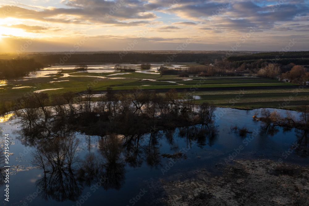 Fototapeta premium Sunset over flooded fields. Sunset reflection in submerged fields. Submerged fields. Afternoon sun reflection in submerged fields.