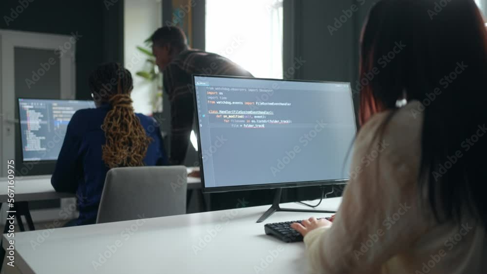 front-end developer working in office, view on display through shoulder, team of data scientists