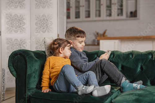 Children using technology at home. Kids have a videochat. Brother and sister watching cartoons or play games.