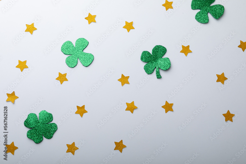 Obraz premium Green shamrocks and golden stars decorations with copy space on white background