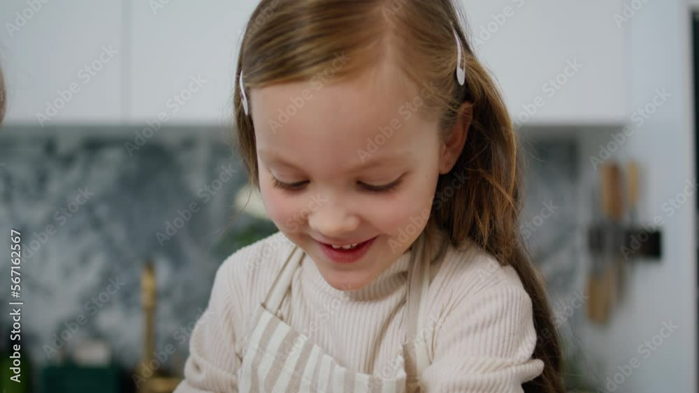 Funny child rolling sleeves up at kitchen portrait. Cute baby baking at home Funny child rolling sleeves up at kitchen portrait. Cute baby baking at home
