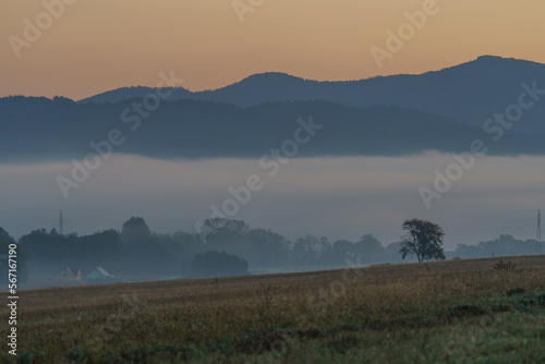 Beautiful sunrise over the mountains in the area of still shaded farmland