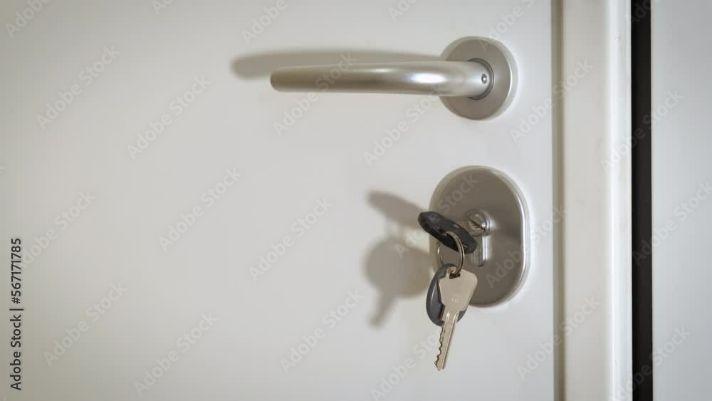 Bunch of keys into hotel door. A metal bunch of keys into the key hole on white door. Bunch of keys into hotel door. A metal bunch of keys into the key hole on white door.