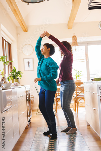 Happy diverse lesbian couple dancing in kitchen