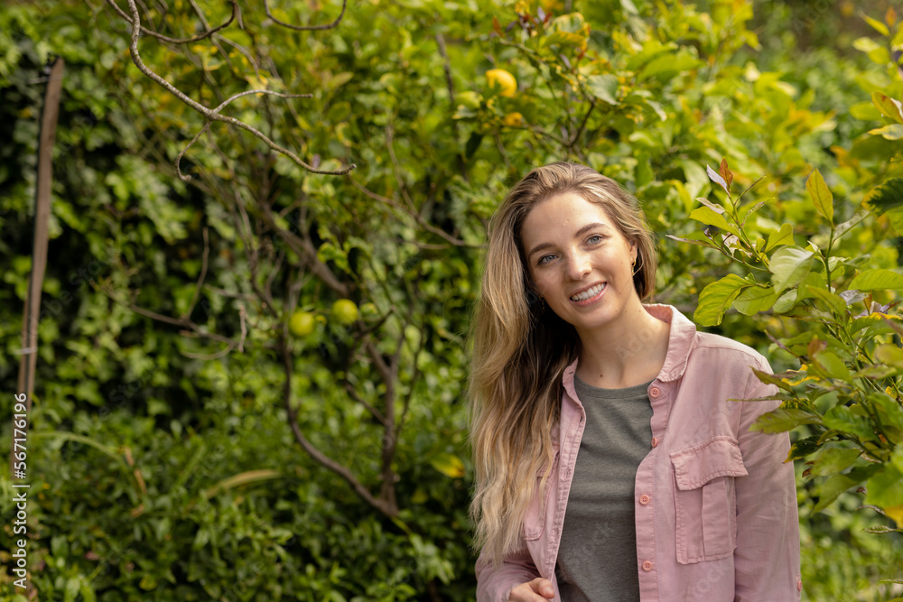 Smiling caucasian woman walking through trees in garden, with copy space Smiling caucasian woman walking through trees in garden, with copy space