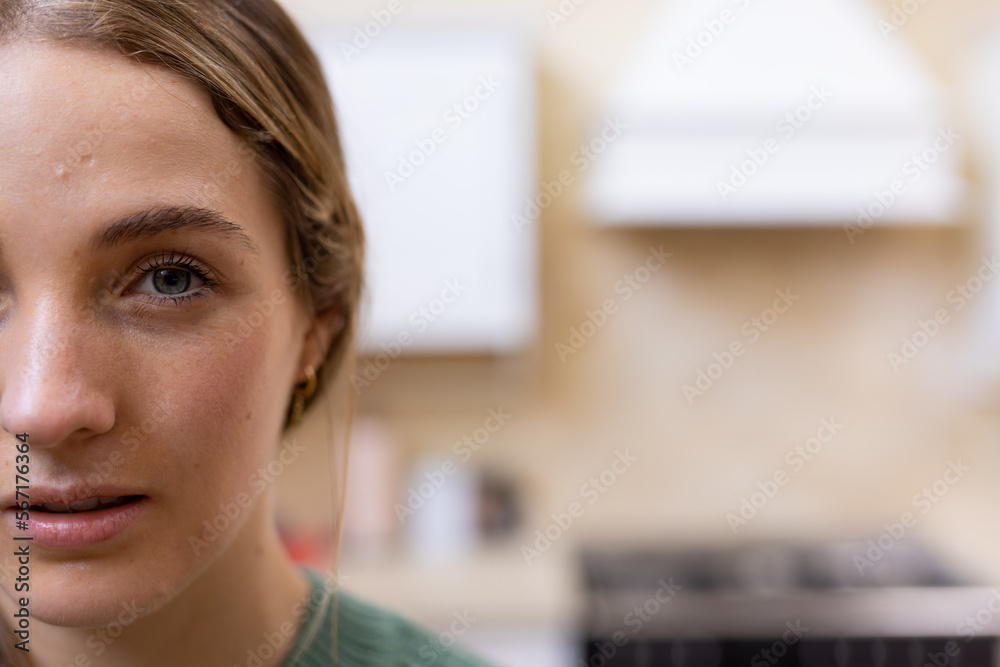 Half face portrait of thoughtful blonde caucasian woman in kitchen at home, copy space