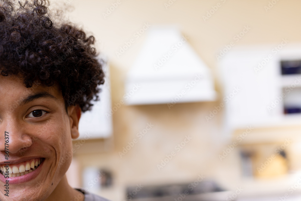 Half face portrait of smiling biracial man with curly hair in kitchen at home, copy space Half face portrait of smiling biracial man with curly hair in kitchen at home, copy space