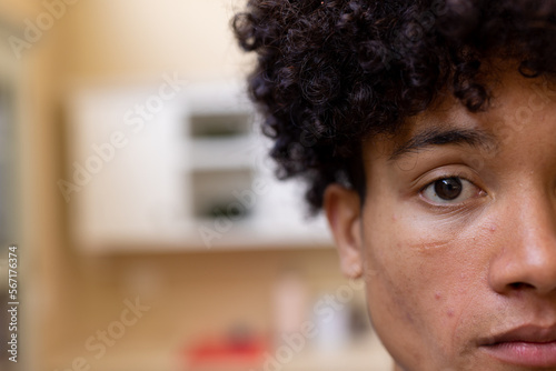 Half face portrait of thoughtful biracial man with curly hair in kitchen at home, copy space photo