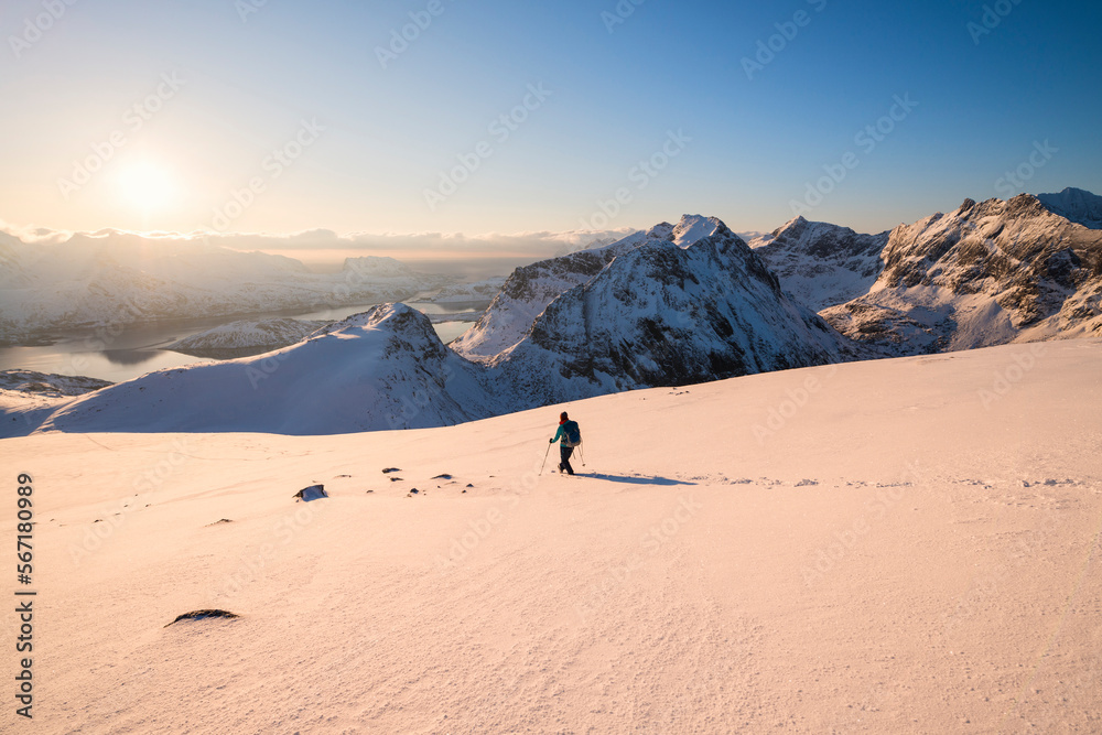 Female hiker descending snowy hillside from summit or Ryten, Moskenesøy, Lofoten Islands, Norway Female hiker descending snowy hillside from summit or Ryten, Moskenesøy, Lofoten Islands, Norway