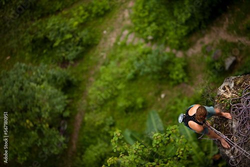 Caucasian female climer looking down from belay station 60 metres above in rural Asia. photo
