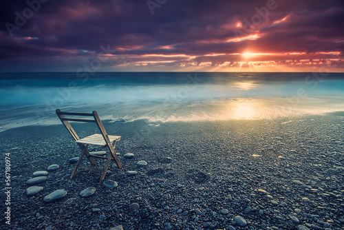 Empty chair on pebble beach under dramatic sky at sunset, Candelaria, Canary Islands, Spain photo
