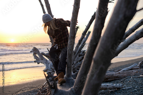 Man standing on fallen tree on beach, Washington State, USA