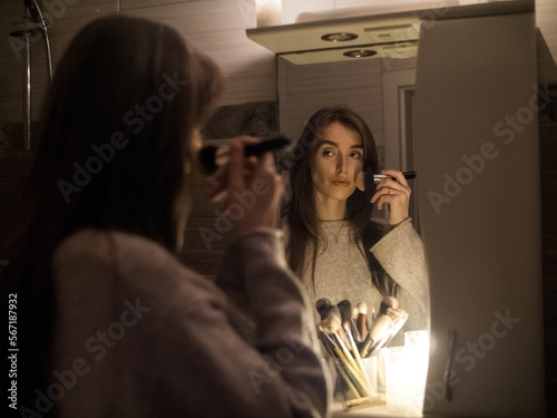 young woman doing make-up in a bathroom without electricity by candlelight