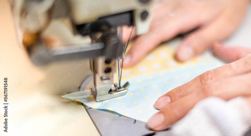 Closeup of the female hand use a sewing machine and cotton fabric at the old sewing machine with vintage style. Closeup of the female hand use a sewing machine and cotton fabric at the old sewing machine with vintage style.