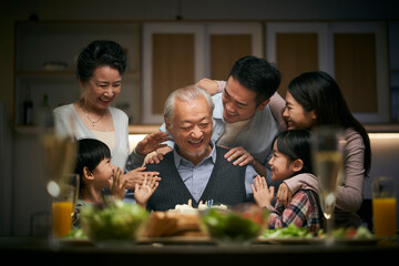 three generation asian family celebrating grandpa's birthday at home
