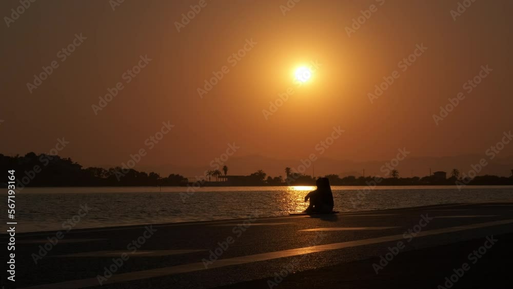 Sea embankment silhouette at sunset. Silhouette of a woman resting at sunset on the sea embankment. Sea embankment silhouette at sunset. Silhouette of a woman resting at sunset on the sea embankment.