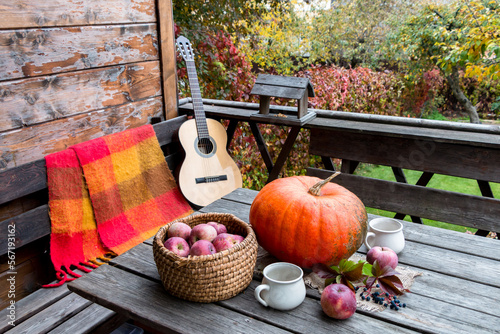 autumn composition with pumpkin and apples and a guitar on an open terrace.  cozy place