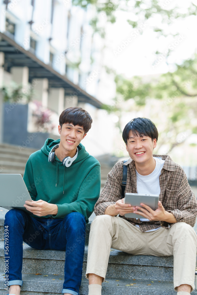 Attractive asian college student using laptop and tablet studying with group of friends together with english language classroom, social media and education concept. Attractive asian college student using laptop and tablet studying with group of friends together with english language classroom, social media and education concept.