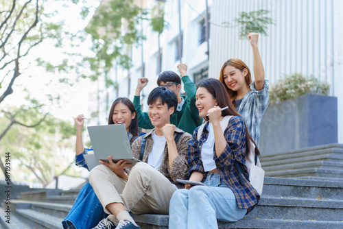 Attractive asian college student using laptop and tablet studying with group of friends together with english language classroom, social media and education concept. © NanSan