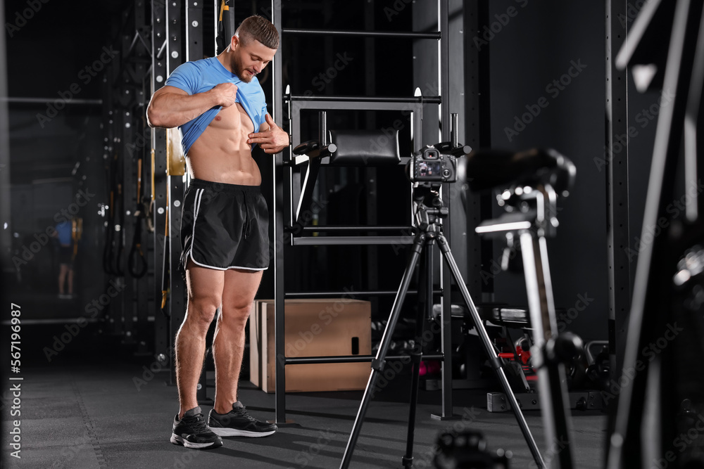 Fototapeta premium Man showing his abs on camera at gym. Online fitness trainer