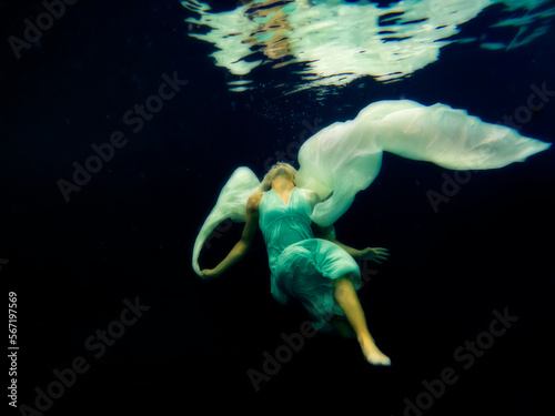 Lexia underwater floating with long dress in pool