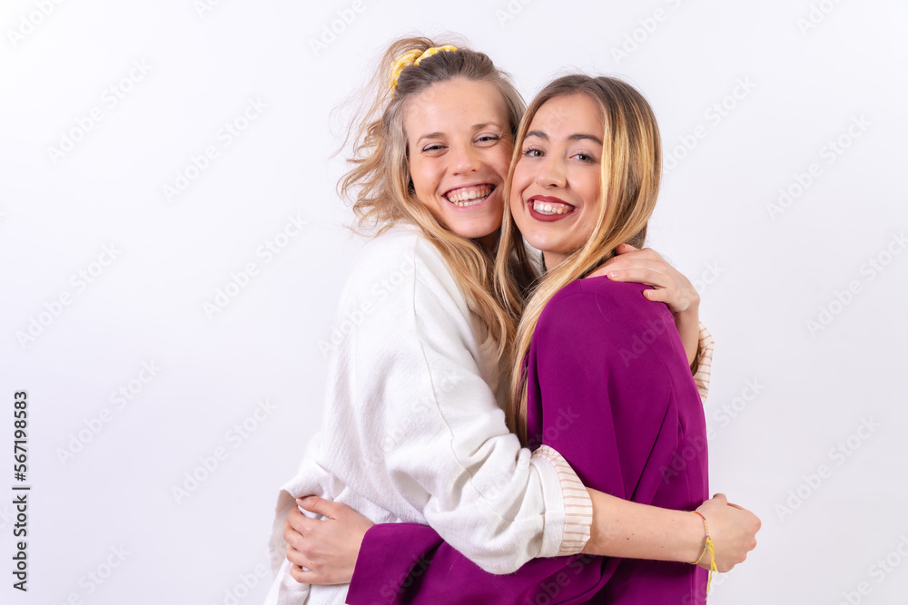 Two young blonde Caucasian women, hugging and smiling, isolated on a white background Two young blonde Caucasian women, hugging and smiling, isolated on a white background