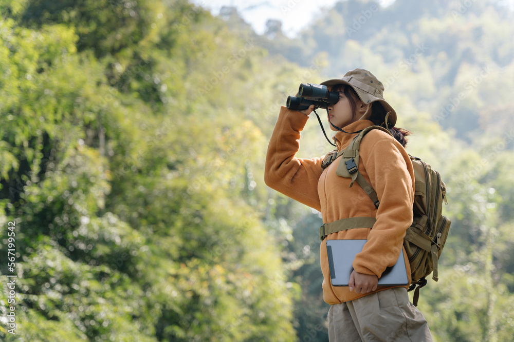 Asian young girl using binoculars in the forest. Explorers and adventurers use binoculars.