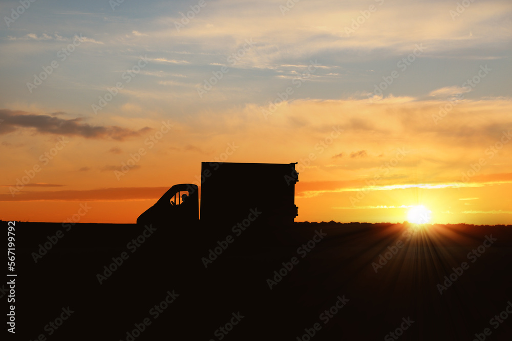 Fototapeta premium Truck driver in vehicle on highway at sunset