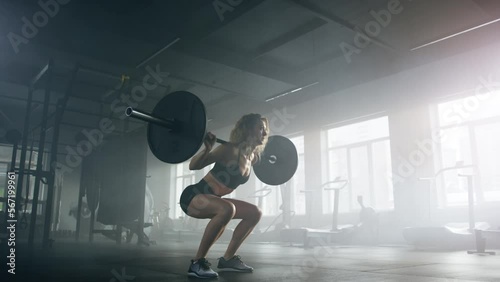 Active, fit lady testing her strength with intensive workout. Close-up view of female powerlifter during a barbell training in dark, modern gym studio. High quality 4k footage