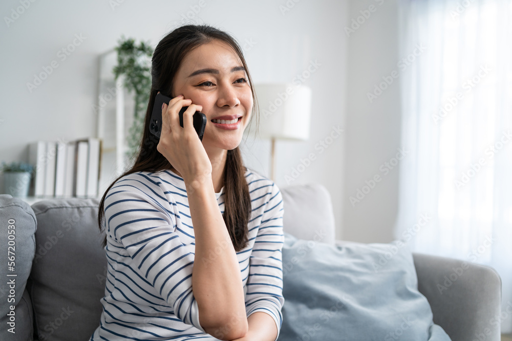 Asian beautiful woman sit on sofa and talk on mobile phone in house. Asian beautiful woman sit on sofa and talk on mobile phone in house.