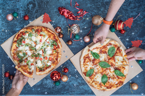 a hand is taking a pizzza slice on a festive Christmas background photo