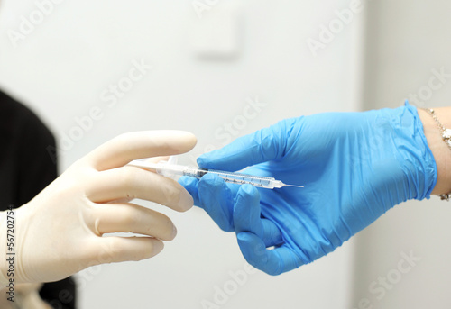 Close up of dental assistant passing syringe to dentist during patient's dental procedure Doctor passing syringe with anesthesia during operation washing gloves close-up people