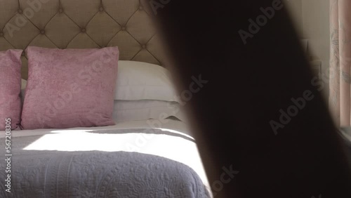 Light beaming through hotel room window onto luxury country bed with comfy pink pillows ready for weekend vacation photo