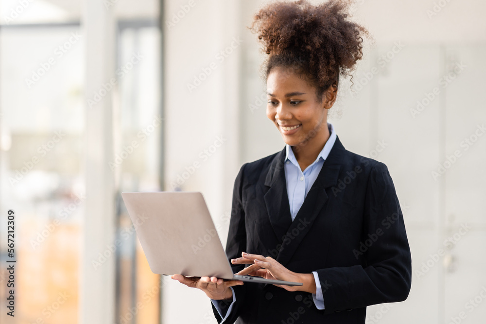 Portrait of attractive cheerful skilled business girl using laptop winking in office over bright background Portrait of attractive cheerful skilled business girl using laptop winking in office over bright background