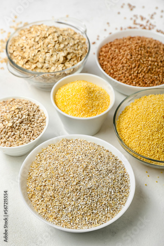 Bowls of different cereals on light background, closeup
