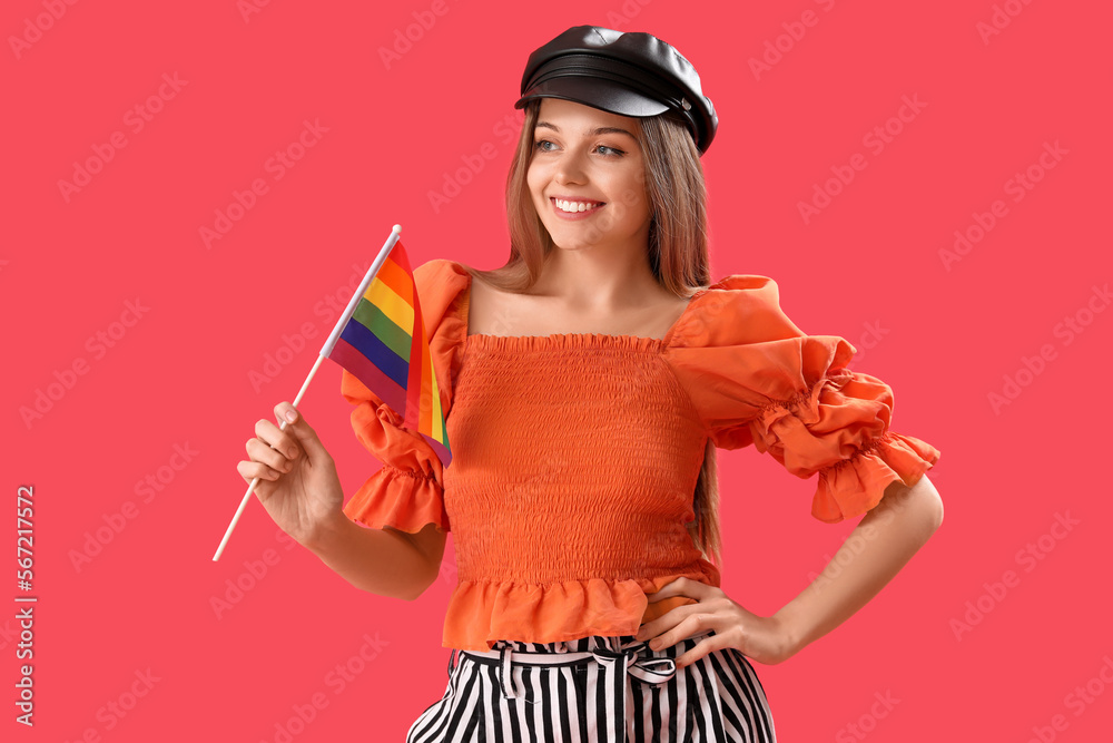 Beautiful young woman in hat with LGBT flag on red background Beautiful young woman in hat with LGBT flag on red background