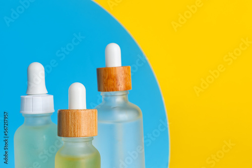 Bottles of natural serum on color background, closeup