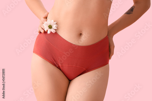 Young woman in menstrual panties with daisy flower on pink background, closeup