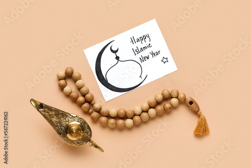 Card with text HAPPY ISLAMIC NEW YEAR, Aladdin lamp and prayer beads on beige background photo