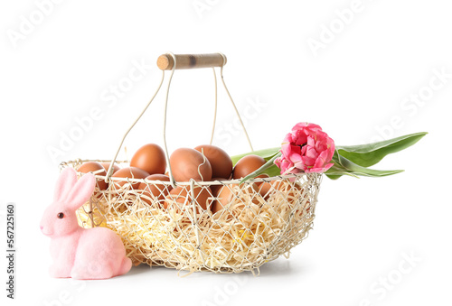 Wicker basket with Easter eggs, pink bunny and tulip flower isolated on white background