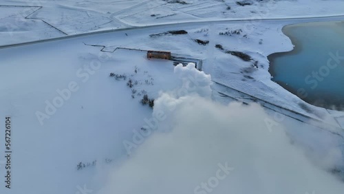 Fast drone dolly shot through the white smoke from Myvatn geothermal installations in the snowy landscape of Iceland.