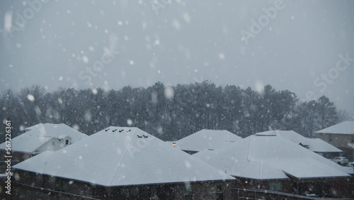 Snow falling with houses and trees in the background photo