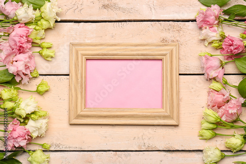 Fototapeta Naklejka Na Ścianę i Meble -  Composition with blank picture frame and flowers on light wooden background