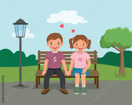 Happy valentine day little couple boy and girl sitting on bench holding hands at the park