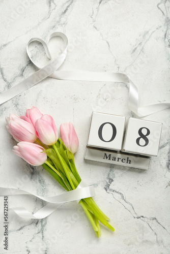 Bouquet of beautiful tulip flowers and cube calendar with date MARCH 8 on light background #567229343