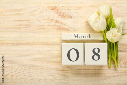 Beautiful tulip flowers and cube calendar with date MARCH 8 on wooden background
