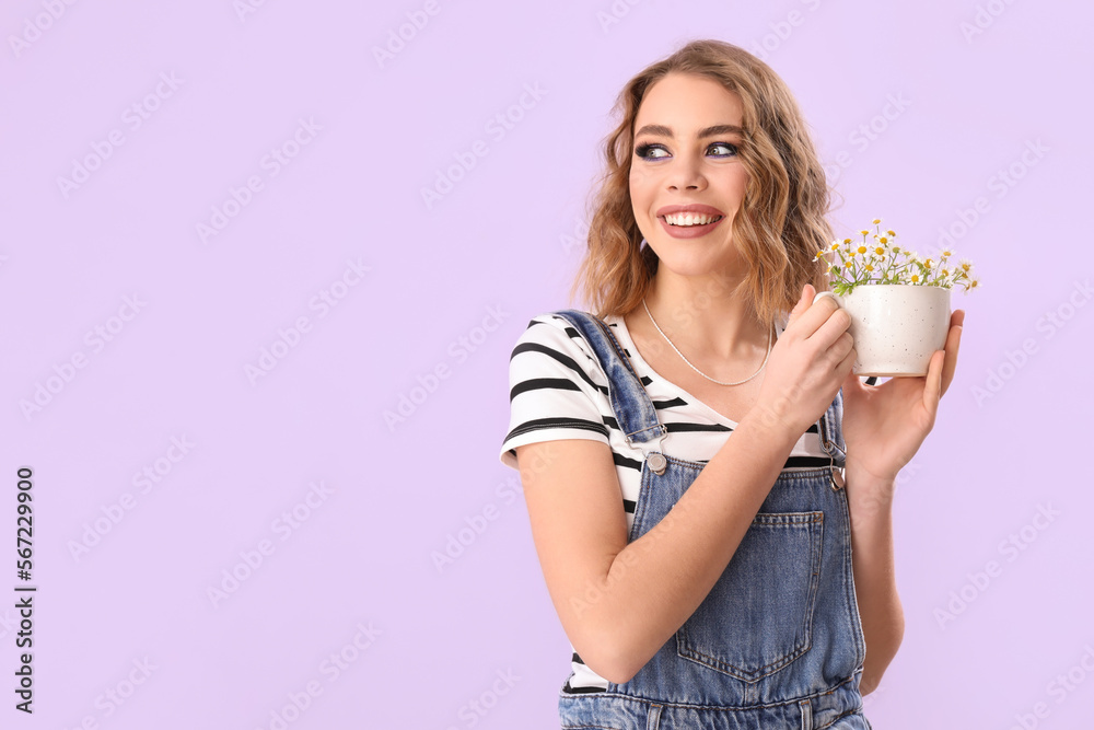 Beautiful happy young woman with chamomiles in cup on lilac background Beautiful happy young woman with chamomiles in cup on lilac background