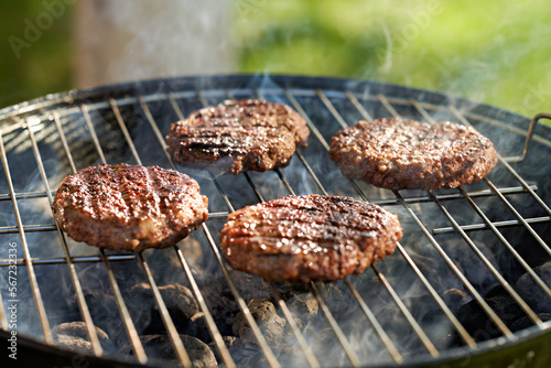 hamburger patties being grilled on charcoal kettle grill