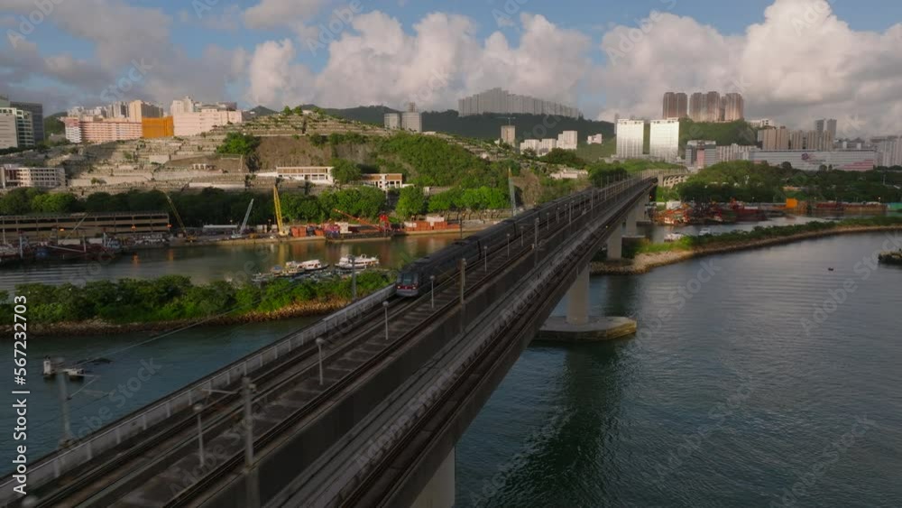 Aerial tracking shot of MTR train (Tung Chung line) from Kwai Chung to Tsing Yi during golden hour. Backwards flight over bridge Aerial tracking shot of MTR train (Tung Chung line) from Kwai Chung to Tsing Yi during golden hour. Backwards flight over bridge